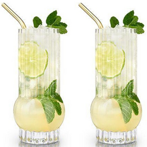 Two highball glasses with a cocktail garnished with lime and mint leaves.  Gold straw in drink.