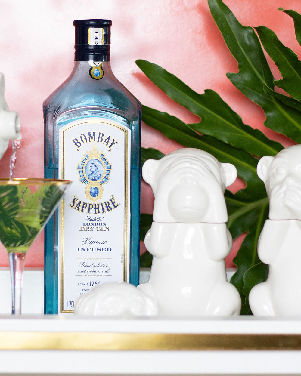 Cute monkey decanters in white ceramic sitting next to a bottle of Sapphire Gin.