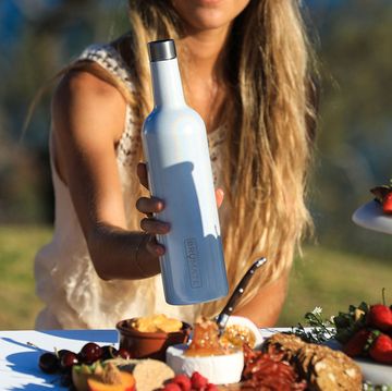 Pretty model placing brumate wine canteen on outdoor table with a charcuterie board.